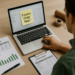 Business owner reviewing inventory reports and financing options at a desk with laptop, packaging materials, and printed inventory charts