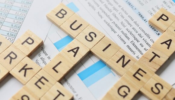 Scrabble tiles spelling out business terms like strategy, market, and profit placed on financial documents and charts.