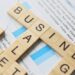 Scrabble tiles spelling out business terms like strategy, market, and profit placed on financial documents and charts.
