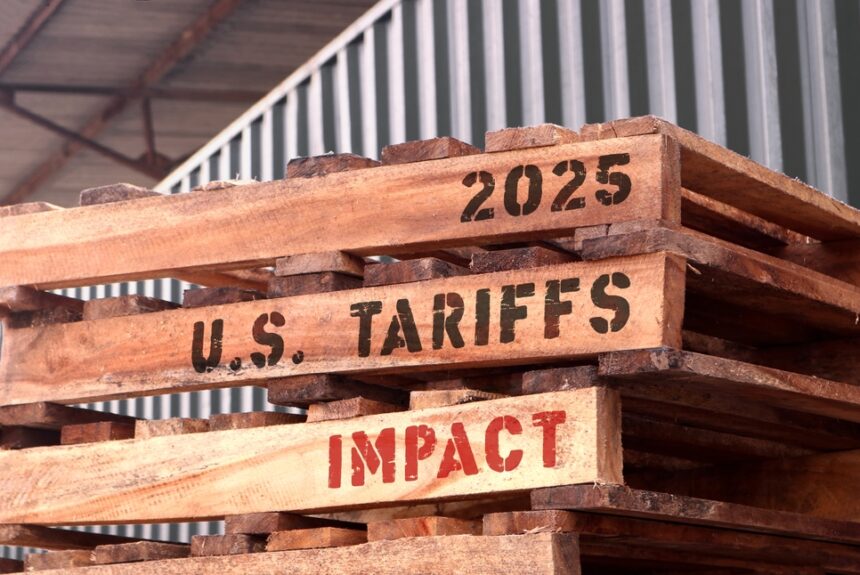 tacked wooden pallets marked with “2025 U.S. Tariffs Impact” outside a warehouse, symbolizing rising costs and supply chain pressure for small businesses