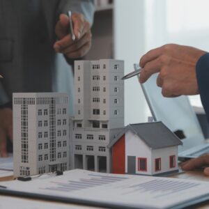 Business professionals reviewing real estate asset-backed lending options with building and house models on a desk surrounded by charts and financial documents