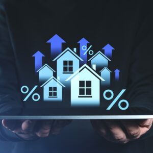 Hands holding tablet with digital houses, percentage signs, and upward arrows symbolizing real estate asset-backed lending growth and ROI
