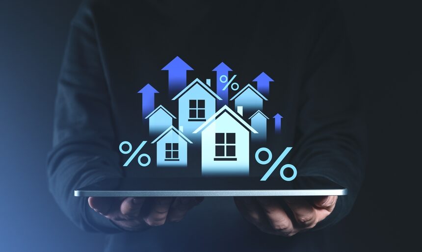 Hands holding tablet with digital houses, percentage signs, and upward arrows symbolizing real estate asset-backed lending growth and ROI