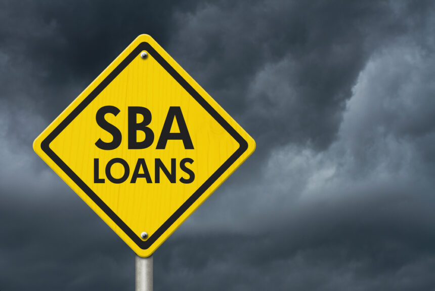 Yellow road sign reading “SBA Loans” with storm clouds in the background, symbolizing upcoming SBA rule changes and challenges in 2025