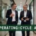 Two finance executives walking through a modern corporate corridor discussing operating-cycle ABL facility design and working capital structuring