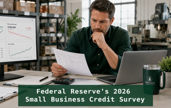 Small business owner reviewing financial reports in a warehouse; Federal Reserve 2026 Small Business Credit Survey