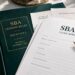 SBA 7(a) loan application documents beside a bound green copy of the SBA lending rules, SOP 50 10 8.1, effective October 1, 2026