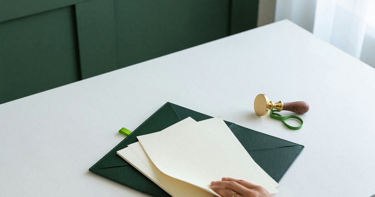Commercial financing contracts and a blank brass seal stamp on a bright desk, illustrating California AB 2116 licensing for business finance providers.
